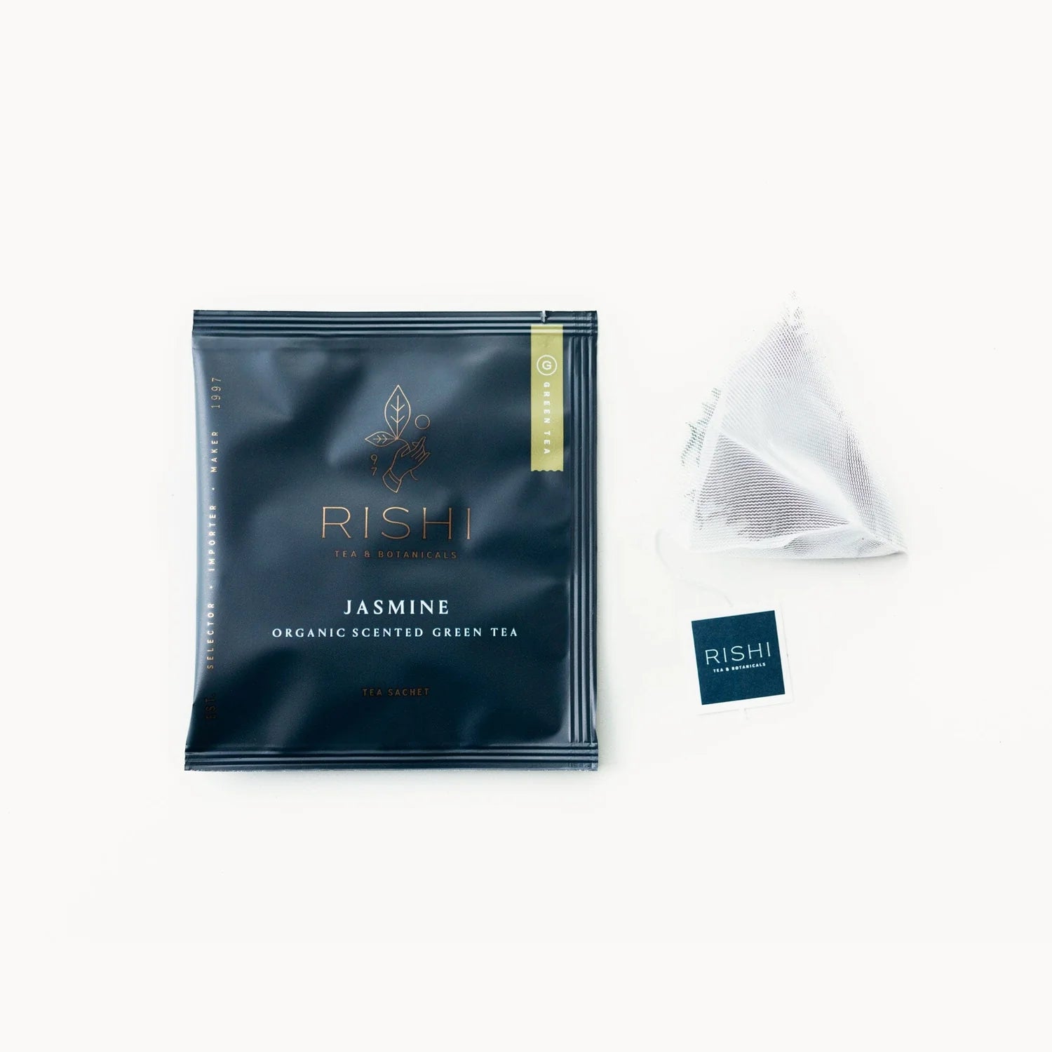 A packaged tea bag with the brand name RISHI and the word JASMINE printed on it, alongside a sealed pyramid tea bag and a small card with the brand name RISHI.