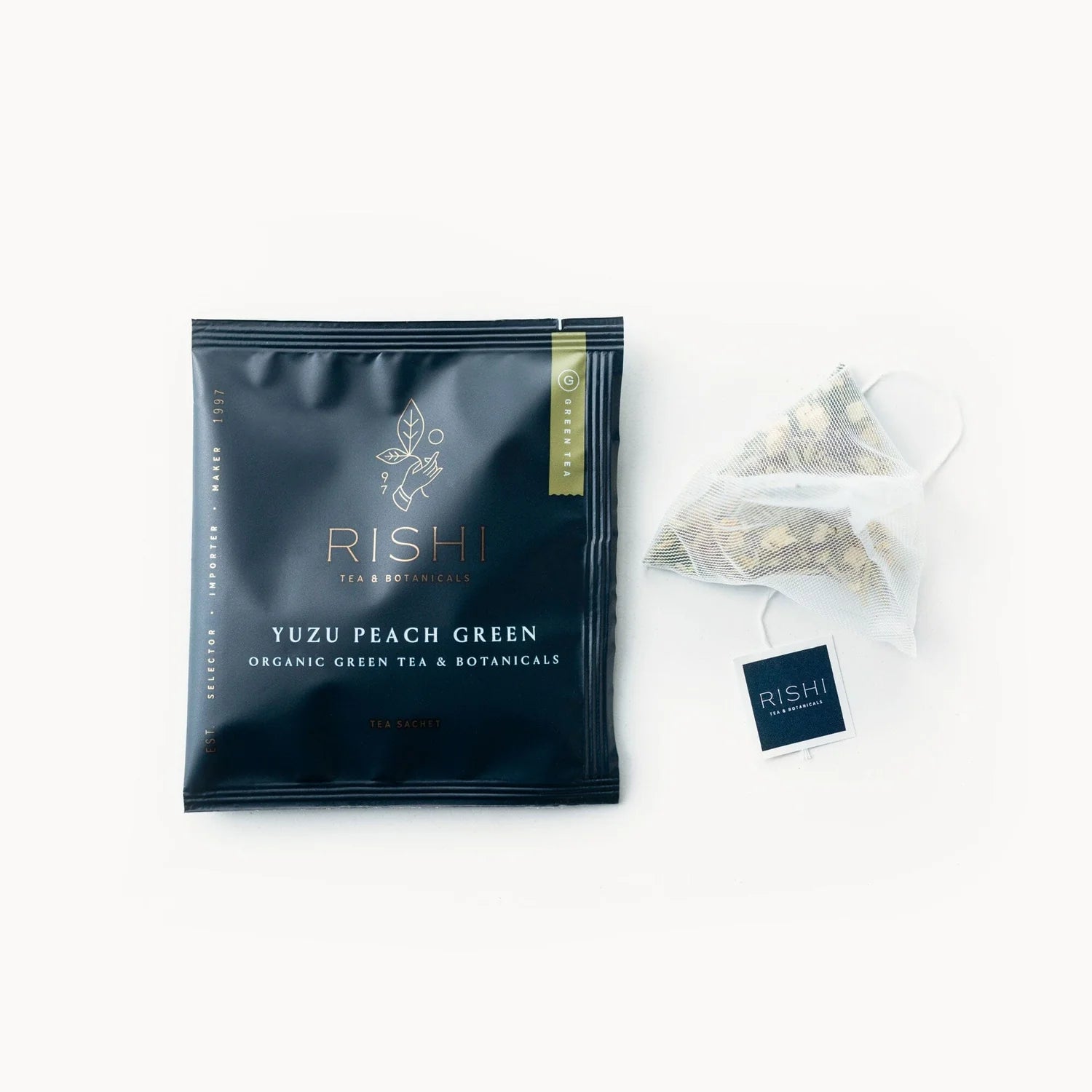 A black tea bag packaging labeled 'RISHI YUZU PEACH GREEN' 